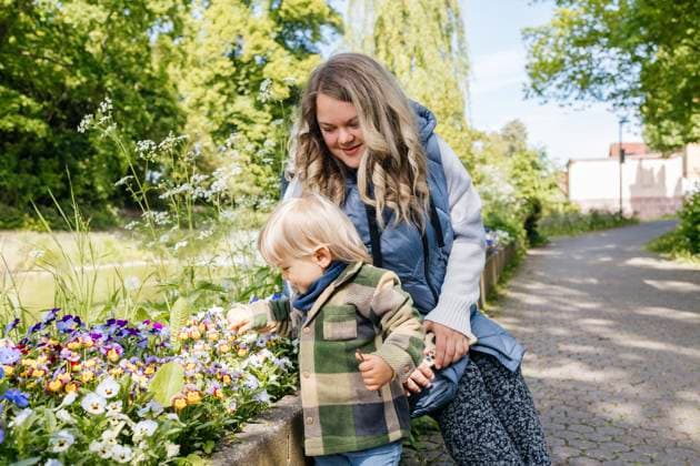 IMAGO Creative, Ostern, Bräuche, Osterspaziergang #2 Mother and baby enjoying a walk by a flowerbed in a park during spring model released, Symbolfoto, ELMF01153