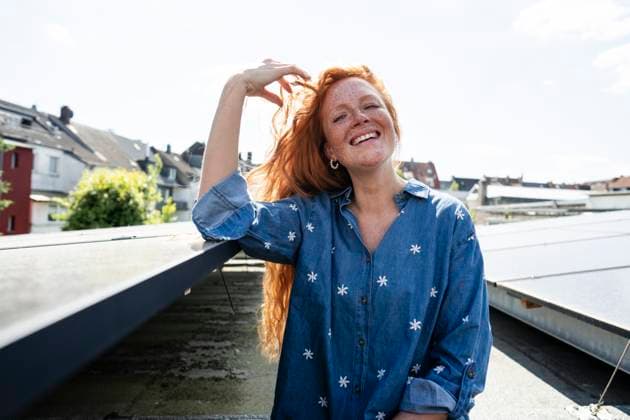 Creative Highlights Symbolbilder Smiling woman with red hair on a rooftop with solar panels model released, Symbolfoto property released, KNSF11369