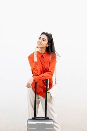 Creative Highlights Symbolbilder Woman in orange shirt with suitcase standing against white wall model released, Symbolfoto, LMCF02492