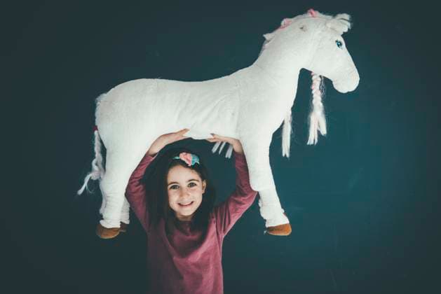 Creative Highlights Symbolbilder Girl holding a toy horse above her head indoors model released, Symbolfoto property released, KNSF11375