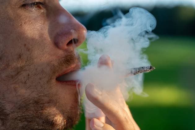 Kammlach, Bavaria, Germany - June 24, 2025: Close-up of a man smoking a cigarette outdoors, thick smoke passes in front of his face *** Nahaufnahme eines Mannes beim Rauchen einer Zigarette im Freien, dichter Rauch zieht vor seinem Gesicht vorbei