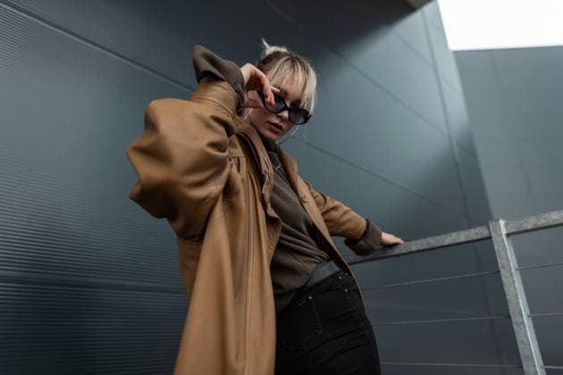 Creative Highlights Symbolbilder Junge schöne Modell Frau mit modischen Sonnenbrille in brauner Lederjacke mit schwarzen Jeans posiert in der modernen Stadt *** Boy Beauty Model Woman with fashionable Sunglasses in Brauner Leather jacket with Black people Jeans poses in the modern City 1102827776
