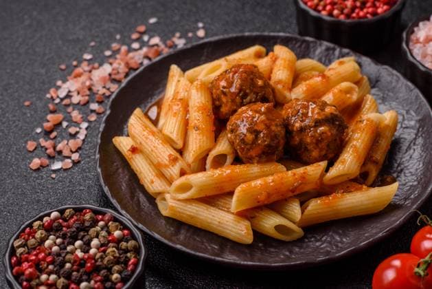 Penne mit Fleischbällchen in Tomatensauce mit Salz und Gewürzen. Italienisches Essen Penne Nudeln Penne pasta with meatballs in tomato sauce with salt and spices. Italian food penne pasta on dark concrete background (License=RF) Copyright: xZoonar.com TetianaxChernykovax 23675798