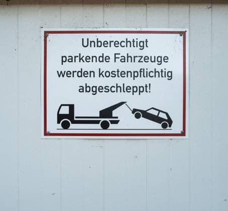 Hinweisschild zur Abschleppandrohung auf Privatgelände Warnhinweis auf einem weißgrundigen Schild mit rotem Rahmen: Unberechtigt parkende Fahrzeuge werden kostenpflichtig abgeschleppt! Darunter eine stilisierte Grafik mit Abschleppfahrzeug und Pkw. Das Schild ist an einer weißen Wand befestigt und weist auf eine drohende kostenpflichtige Maßnahme hin, um unbefugtes Parken zu verhindern. Der Hinweis richtet sich an Falschparker auf einem privaten oder firmeneigenen Gelände. *** Warning sign for towing threat on private property Warning on a white-ground sign with red frame Unauthorized parked vehicles will be towed away for a fee Below a stylized graphic with tow truck and car The sign is attached to a white wall and indicates an Copyright: xEibner-Pressefotox EP_EER