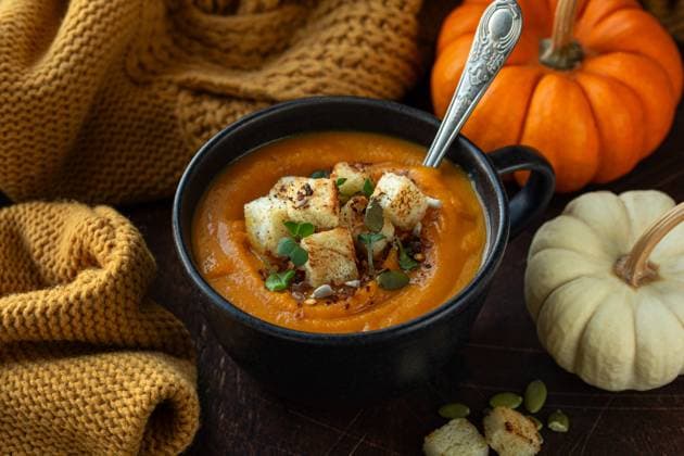 leckere vegane Kürbissuppe im schwarzen Becher, serviert mit Kürbiskernen und Croutons, dunkler Hintergrund tasty vegan pumpkin soup in black mug, served with pumpkin seeds and croutons, dark background (License=RF) Copyright: xZoonar.com Anna_Shepulovax 23676115