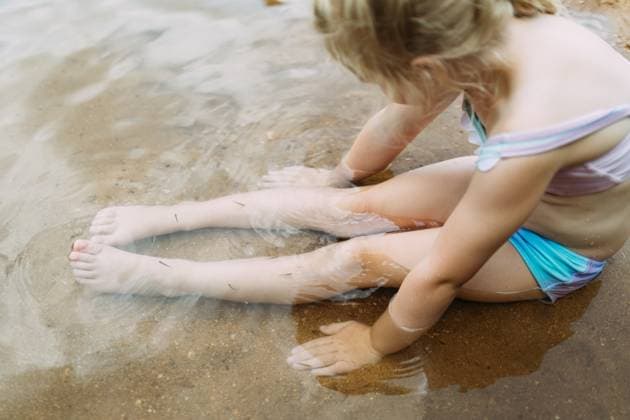 Creative Highlights Symbolbilder Child sitting in shallow sandy water surrounded in tiny fish Grassy, Missouri, United States CR_WEKW250628-1774354-01 ,model released, Symbolfoto