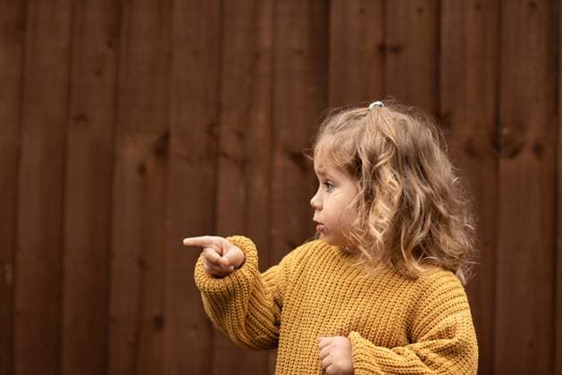 Creative Highlights Symbolbilder Toddler girl in yellow sweater pointing away. Corby, England, United Kingdom R_JNDO250628A-1767273-01 ,model released, Symbolfoto