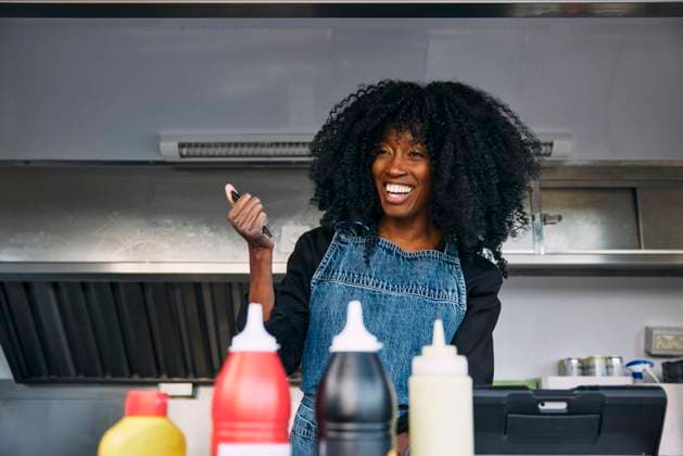 Creative Highlights Symbolbilder Happy curly haired female owner wearing apron holding pen looking away while standing in food truck Sweden, Stockholm, model released, property released Copyright: xMaskotx , MA118431 MA118431