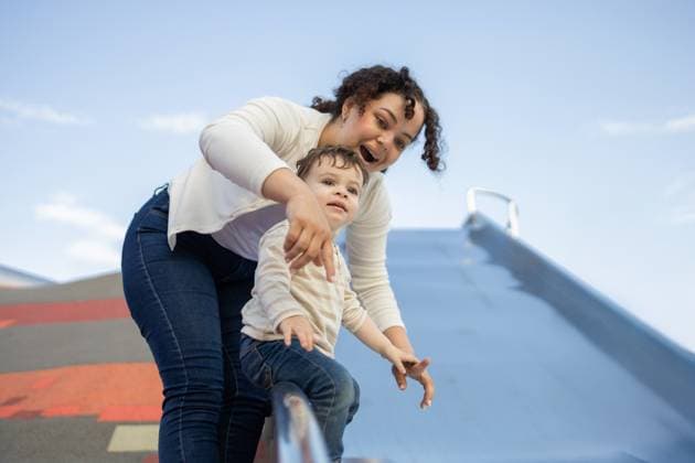 Creative Highlights Symbolbilder A joyful mother assists her baby on a playground slide in a sunny park. The image captures the excitement and bonding between mother and child during outdoor playtime. Model Released DavidMunoz_ID29315_965746_018 Copyright: xDavidxMunozx