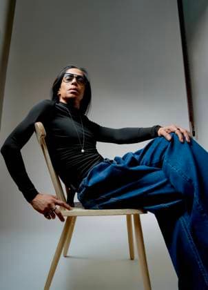 Creative Highlights Symbolbilder MR_ID28559_21038_RichardOchoa.jpg A portrait of a stylish Latin man sitting on a wooden chair, wearing a sleek black long-sleeve shirt and blue jeans. His confident pose exudes casual elegance Model Released DondykRiga_ID28559_841375_008 Copyright: xDondykxRigax RECORD DATE NOT STATED