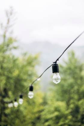 MR_ID29414_21446_OlhaHusonka.jpg String lights hang delicately against a lush, green mountain backdrop, capturing the serene ambiance of a rainy morning. Gentle raindrops settle on the bulbs Model Released HannaYakimenko_ID29414_1000839_008 Copyright: xHannaxYakimenkox