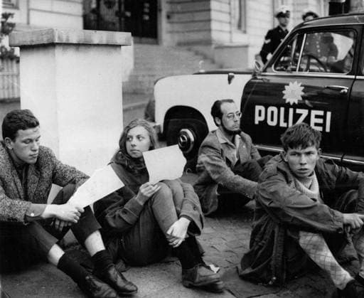 Demonstrationen 24. April 1962 - Sitzstreik vor dem US-Konsulat in Hamburg: 20 schwedische Studenten begannen heute Abend einen Sitzstreik vor dem amerikanischen Konsulat. Sie brachten damit ihren Protest gegen die Wiederaufnahme amerikanischer Atomtests zum Ausdruck. Die Hamburger Polizei postierte Streifenwagen vor dem Konsulat, um Zwischenfälle zu vermeiden. Das Foto zeigt schwedische Studenten zwischen Streifenwagen vor dem amerikanischen Konsulat in Hamburg. *** Demonstrations 24 April 1962 Seat Strike before the US Consulate in Hamburg 20 Swedish Students began Today Evening a Seat Strike before the American Consulate you brought So their Protest against the Resumption American Nuclear tests to Printout the Hamburg Police posted  Copyright: xUnitedxArchivesx xkpaxKeystonex 19620424_baf_k09_003