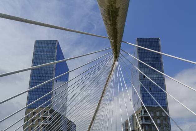 Moderne Brückenseile überlagern Wolkenkratzer unter blauem Himmel, Bilbao, Baskenland, Spanien, Europa Modern bridge cables overlay skyscrapers under a blue sky, Bilbao, Basque Country, Spain, Europe Copyright: imageBROKER StephanxSuehling iblssh13994822.jpg