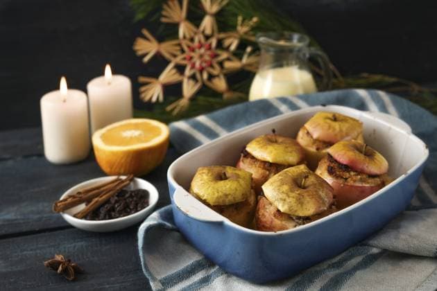 Deutsche Bratäpfel gefüllt mit Mandeln, Marzipan und Honig in einer Kasserolle, Zutaten, Kerzen und Weihnachtsdekoration vor dunkelblauem Hintergrund, festliches Weihnachtsdessert, ausgewählter Fokus German baked apples filled with almonds, marzipan and honey in a casserole, ingredients, candles, and Christmas decoration against a dark blue background, festive holiday dessert, selected focus Copyright: imageBROKER MarenxWinter ibxiqx11195343.jpg