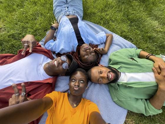 Glückliche Gruppe von afroamerikanischen Freunden Mädchen und Jungs herumalbern, ruhen auf Gras, machen Selfie während Grimassen schneiden. Zufriedene vier schwarze Studenten, die im Rasen liegen, machen ein Foto mit dem Handy, haben Spaß zusammen Happy group of african american friends girls and guys fool around, resting on grass, make selfie while grimacing. Satisfied four black students lying in lawn take picture on phone, have fun together Copyright: imageBROKER DmitriixMarchenko ibxiqx14265031.jpg ,model released, Symbolfoto ,property released