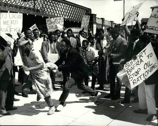 Demonstrationen 8. August 1967 Protestierende biafranische Studenten: In Kriegstanz-Montur führten biafranische Studenten heute eine Prozession zur Downing Street und zum Shell Centre am South Bank an, um gegen die Rolle von Shell-BP und der britischen Regierung im Nigeria-Konflikt zu protestieren. Das Foto zeigt biafranische Studenten, die heute unter Beobachtung der Polizei einen Kriegstanz aufführen, während sie vor dem Shell-BP-Gebäude auf ihren Anführer warten. *** Demonstrations 8 August 1967 Protesters Biafran Students in War dance Montur led Biafran Students Today a Procession to Downing Street and to Shell Centre on South Bank to, at against the Role from Shell BP and the British Government at Nigeria Conflict to Pr  Copyright: xUnitedxArchivesx xkpaxKeystonex 19670808_baf_k09_196