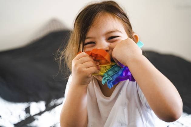 Creative Highlights Symbolbilder Kleinkind Mädchen mit Popit Spielzeug in Regenbogenfarben. Silikonspielzeug in Dinoform zum Stressabbau. Bubbles sensorische trendige zappeln. Kind spielt zu Hause im offenen Stil Toddler girl with popit toy in rainbow colours. Dino shape silicone toy for stress relief. Bubbles sensory trendy fidget. Child playing at home in candid style. Copyright: imageBROKER AlexandraxTroyan ibxiqx13808144.jpg ,model released, Symbolfoto ,property released
