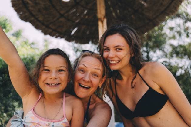 Glücklicher Familienmoment mit einem jungen Mädchen, einer Mutter und einer älteren Tochter, die unter einem Strohschirm am Pool posieren und Freude und Zusammengehörigkeit ausstrahlen Happy family moment with a young girl, mother, and older daughter posing under a straw umbrella near the pool, radiating joy and togetherness. Copyright: imageBROKER AlexandraxTroyan ibxiqx13809692.jpg ,model released, Symbolfoto ,property released
