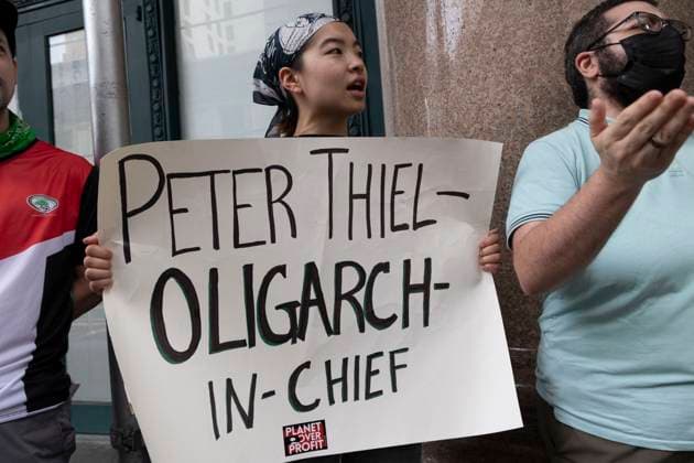 July 14, 2025, New York, New York, USA: A demonstrator with Planet Over Profit holds a sign that reads PETER THIEL OLIGARCH-IN-CHIEF as protesters blockade the entrance to the software company Palantir denouncing their work with U.S. Immigration and Customs Enforcement (ICE) and weapons manufacturers. In ManhattanÃ¢â‚¬â ¢s Chelsea neighborhood protesters call for Palantir to stop supplying tech that supports Trump administration tracking of migrants for deportation and weapons used by Israel in Gaza. Multiple demonstrators are arrested by NYPD. New York USA - ZUMAr174 20250714_znp_r174_026 Copyright: xGinaxMxRandazzox