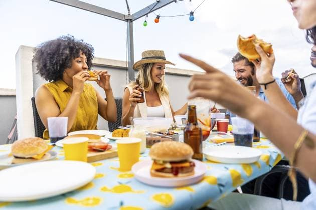 Fröhliche Freunde genießen Burger und Bier und feiern ihre Zweisamkeit auf einer Dachterrasse mit Lichterketten Happy friends enjoying burgers and beer, celebrating togetherness on a rooftop with string lights Copyright: imageBROKER UnaixHuizi ibxuhu14211844.jpg ,model released, Symbolfoto ,property released