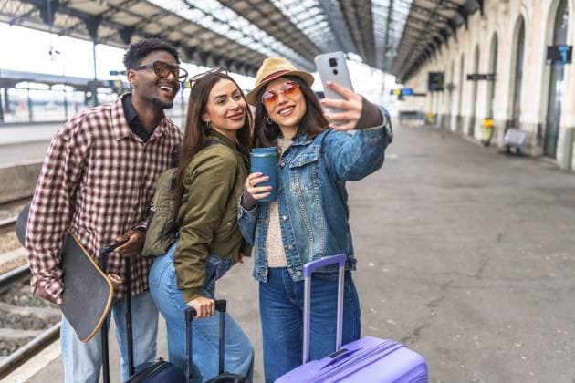 Drei glückliche junge Touristen machen ein Selfie mit einem Smartphone, während sie auf ihren Zug warten, bereit für ihr nächstes Abenteuer Three happy young tourists taking a selfie with a smartphone while waiting for their train, ready for their next adventure Copyright: imageBROKER UnaixHuizi ibxuhu14216911.jpg ,model released, Symbolfoto ,property released