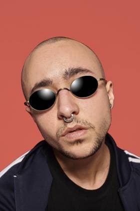 Nahaufnahme eines gutaussehenden, tätowierten Mannes mit Sonnenbrille und Nasenring, der ein schwarzes, modisches T Shirt mit Aufdruck und einen Sportanzug trägt und in die Kamera schaut, während er vor einem rosafarbenen Hintergrund mit Copy Space posiert. Menschen, Stil und Mode Konzept. 90er Jahre Stil Close-up studio shot of a handsome tattoed bald man in sunglasses, with a pirsing ring in his nose, wearing black trendy t-shirt with print and sport suit, looking at the camera while posing against a pink background with copy space. People, style and fashion concept. 90s style Copyright: imageBROKER SerhiixNazarov ibxiqx14221003.jpg ,model released, Symbolfoto ,property released