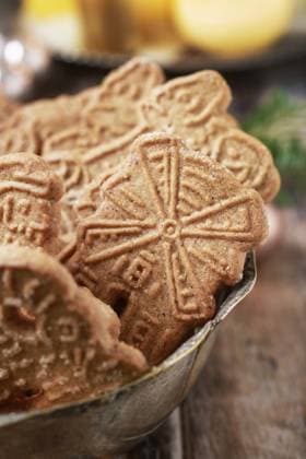 Bowl of speculaas biscuits, golden candles in the background. Festive party dessert  BEW1EA6D5AA