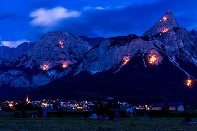 Bergfeuer Ehrwald (Mountain Fires), view to mountain Ehrwalder Sonnenspitze, visitors: Every year on the weekend around St. John s Day (summer solstice, June 21), the imposing mountain scenery surrounding the Ehrwald-Lermoos-Biberwier valley basin is transformed into a unique experience during the traditional solstice fires, with the laying out of large figures made from thousands of incendiary devices. The figures range from Christian symbolism and motifs from the flora and fauna to depictions of complex images. Additional laying out of chains of fire along the mountain ridges. Ehrwald Tiroler Zugspitz Arena Tirol, Tyrol Austria