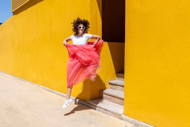 Creative Highlight Symbolbilder Woman holding skirt and jumping from steps near yellow wall model released, Symbolfoto, LMCF01442