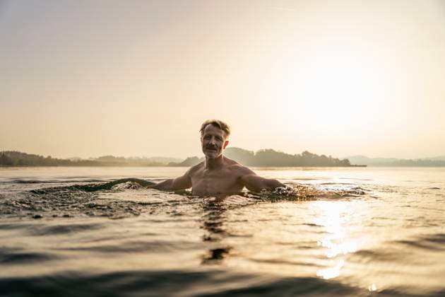 Creative Highlight Symbolbilder Elderly man swimming in lake at sunrise model released, Symbolfoto, DIGF21627