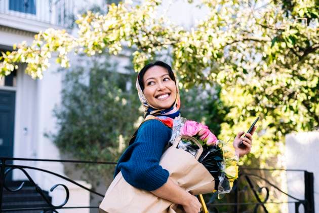 Creative Highlight Symbolbilder Smiling woman with headscarf holding flowers and shopping bag outdoors model released, Symbolfoto, AMWF03366