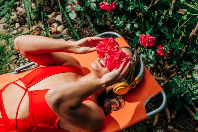 Creative Highlight Symbolbilder Woman in red swimsuit relaxing in a garden with roses in summer model released, Symbolfoto, VSNF03533