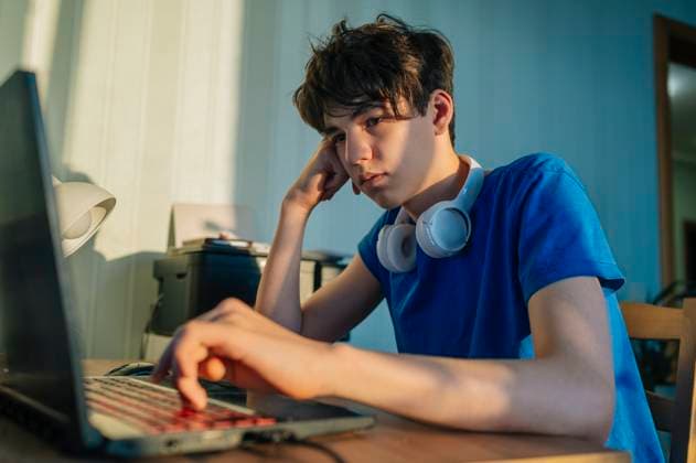 Sad teenager learning online with laptop and headphones at desk model released, Symbolfoto property released, ANAF04828