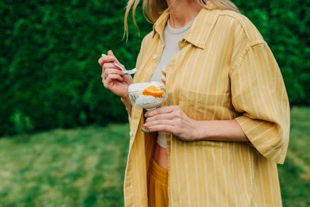 Creative Highlight Symbolbilder Person in yellow shirt holding ice cream outdoors in summer garden model released, Symbolfoto, VSNF03595