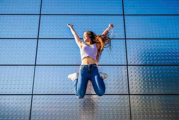 Creative Highlight Symbolbilder Joyful teenage girl jumping with headphones against urban blue wall outdoors model released, Symbolfoto, FOMF00079