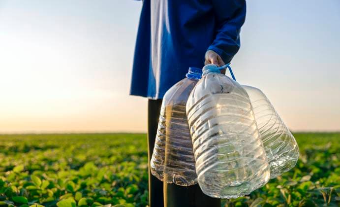 Creative Highlight Symbolbilder Woman holding plastic bottles in field promoting sustainability model released, Symbolfoto, MBLF00941