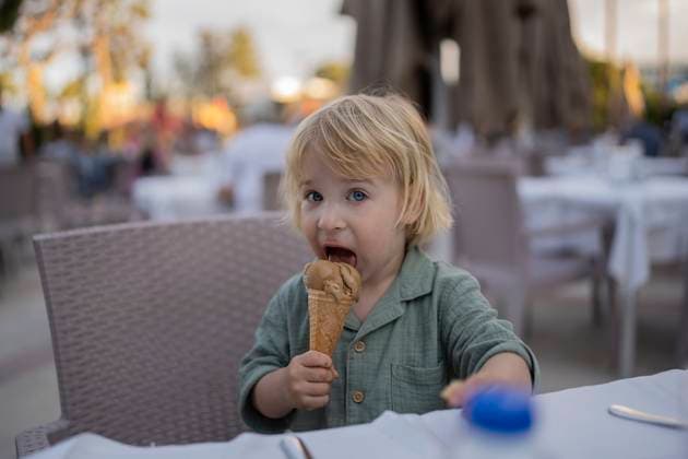 Creative Highlight Symbolbilder Child enjoying chocolate ice cream outdoors at a restaurant table model released, Symbolfoto, OGSF00168