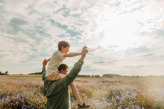 Creative Highlight Symbolbilder Father carrying son on shoulders in summer meadow with purple cornflowers model released, Symbolfoto, VSNF03701