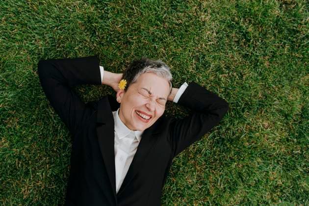 Creative Highlight Symbolbilder Businesswoman in suit relaxing and laughing on grass outdoors model released, Symbolfoto, YTF04038