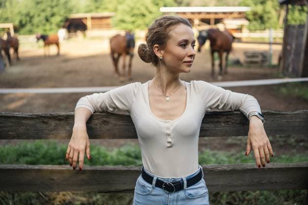 Creative Highlights Symbolbilder Woman at horse ranch leaning on wooden fence, relaxed. Orenburg, Orenburg Oblast, Russia R_LQBD250721-1793202-01 ,model released, Symbolfoto