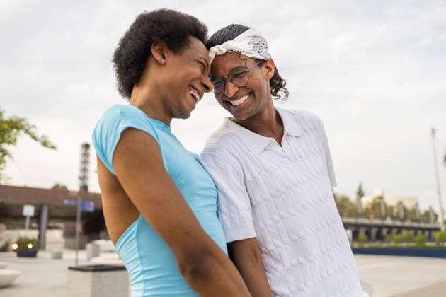 A joyful queer couple laughing together in a sunny outdoor setting, embodying happiness and love while enjoying the warm summer day. Their closeness highlights connection. Model Released DavidMunoz_ID30311_1023005_011 Copyright: xDavidxMunozx