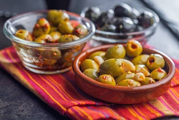 Tapas. Aromatisierte eingelegte Oliven in einer Schale auf einer Serviette. Tapas. Flavored pickled olives in bowl on a kitchen napkin. (License=RF) Copyright: xZoonar.com JirixHERAx 23787902
