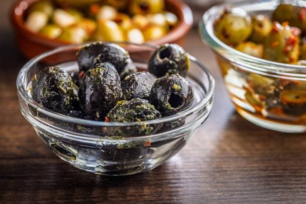 Tapas. Aromatisierte eingelegte Oliven in einer Schale auf einem Holztisch. Tapas. Flavored pickled olives in bowl on a wooden table. (License=RF) Copyright: xZoonar.com JirixHERAx 23787917