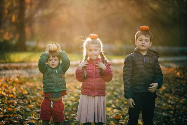 Children balancing pumpkins on their heads in autumn park North Andover, Massachusetts, United States CR_FKNH250723-1791630-01 ,model released, Symbolfoto
