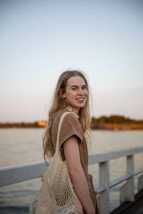 Creative Highlights Symbolbilder Portrait of young woman smiling on pier at sunset by the Baltic Sea Helsinki, Uusimaa, Finland CR_PJJZ250725-1795404-01 ,model released, Symbolfoto