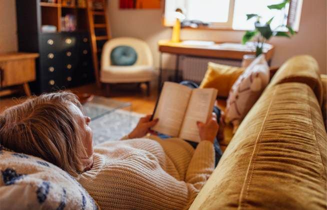 Eine ältere Frau in Freizeitkleidung liegt auf der Couch und liest einen Roman An elderly woman in casual clothes is lying on the couch and reading a novel. A mature lady holds a book and relaxes at home on the sofa in the bedroom. Stylish, modern and cozy interior (License=RF) ,model released, Symbolfoto Copyright: xZoonar.com DashaxPetrenkox 23796856 ,model released, Symbolfoto ,property released
