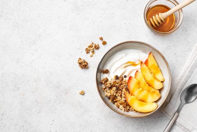 Müslischale mit griechischem Joghurt, Pfirsich und Honig Granola bowl for healthy breakfast. Homemade granola with greek yogurt, peaches and honey on white background, top view, copy space. Healthy eating, seasonal summer breakfast template. (License=RF) Copyright: xZoonar.com OksanaxBratanovax 23796740