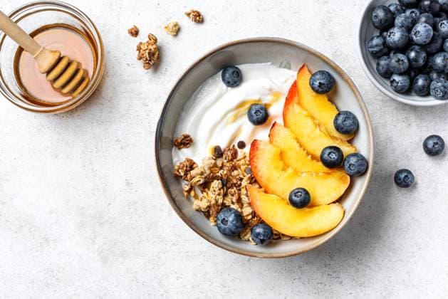 IMAGO Creative, Food, High Protein Frühstück Müslischale mit griechischem Joghurt, Pfirsich und Heidelbeeren Granola bowl for healthy breakfast on white concrete background, top view. Homemade granola with greek yogurt, peaches and blueberries. Healthy eating, seasonal summer breakfast template. (License=RF) Copyright: xZoonar.com OksanaxBratanovax 23796763
