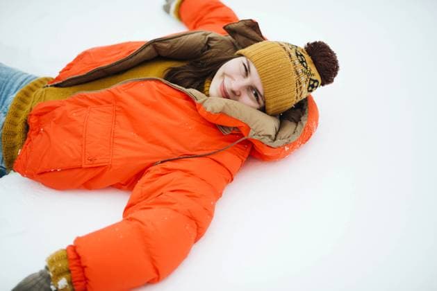 Creative Highlights Symbolbilder Young woman in orange jacket laying on the ground after a fresh R_INCH210305B-671700-01 ,model released, Symbolfoto