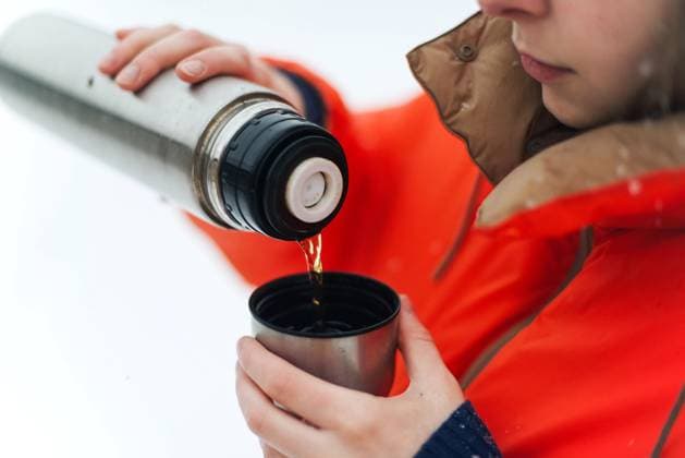 Creative Highlights Symbolbilder Woman in orange jacket pouring herself a warm cup of hot tea ou R_INCH210305B-671709-01 ,model released, Symbolfoto